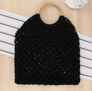 Handwoven beach tote bag with intricate black macrame design and wooden handle on a striped background.