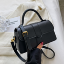 women's commuter messenger bag in black held by a person with a stylish outfit on a light background