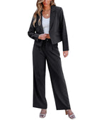 A woman wearing a black womens business suit set, featuring a cropped blazer and wide-leg pants, paired with a white top.