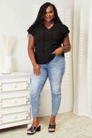 Eyelet flutter sleeve top paired with jeans, showcasing a curve model in a stylish indoor setting.