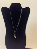 women's pendant necklace featuring a sparkling letter 'R', displayed on a jewelry stand.