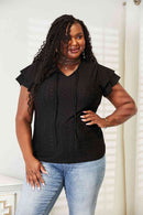 Eyelet flutter sleeve top with tie-neck design, modeled by a plus-size woman wearing jeans.