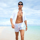 Man in casual men's summer stripe shorts walking on the beach, enjoying the summer sun.