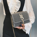 Fringe crossbody bag in gray with gold chain, stylish small square shoulder bag, held by a person wearing a white blouse.