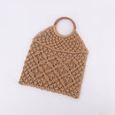 Handwoven beach tote bag made of cotton rope with a wooden handle, perfect for a stylish beach outing.