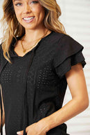 Eyelet flutter sleeve top in black with tie-neck and flutter sleeves, showcasing a stylish and feminine design.