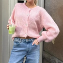 Women's woolen cardigan in soft pink, paired with casual jeans and holding a green drink.