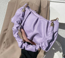 Versatile crossbody shoulder bag in lavender with a stylish ruffled design held by a hand.