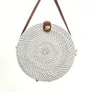 Colorful straw bucket bag with round woven design and brown strap, perfect for sunny outings.