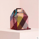 Checkered crossbody shoulder bag in vibrant colors displayed on a pedestal against a soft pink background.