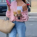 woman holding coffee and phone while wearing a stylish women's woolen cardigan and casual jeans