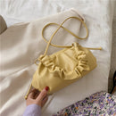 Versatile crossbody shoulder bag in yellow, featuring a chic scrunched design and an adjustable strap on a textured background.