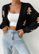 Women wearing a stylish women's gingerbread cardigan with a black background and gingerbread man embellishments.