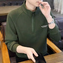 Men's fleece hoodie jacket in dark green, featuring a half zipper and ribbed texture, worn comfortably in a casual setting.